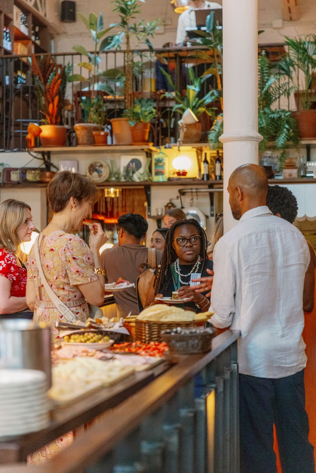 Guests gathered around the grazing table in the restaurant, plates in hand