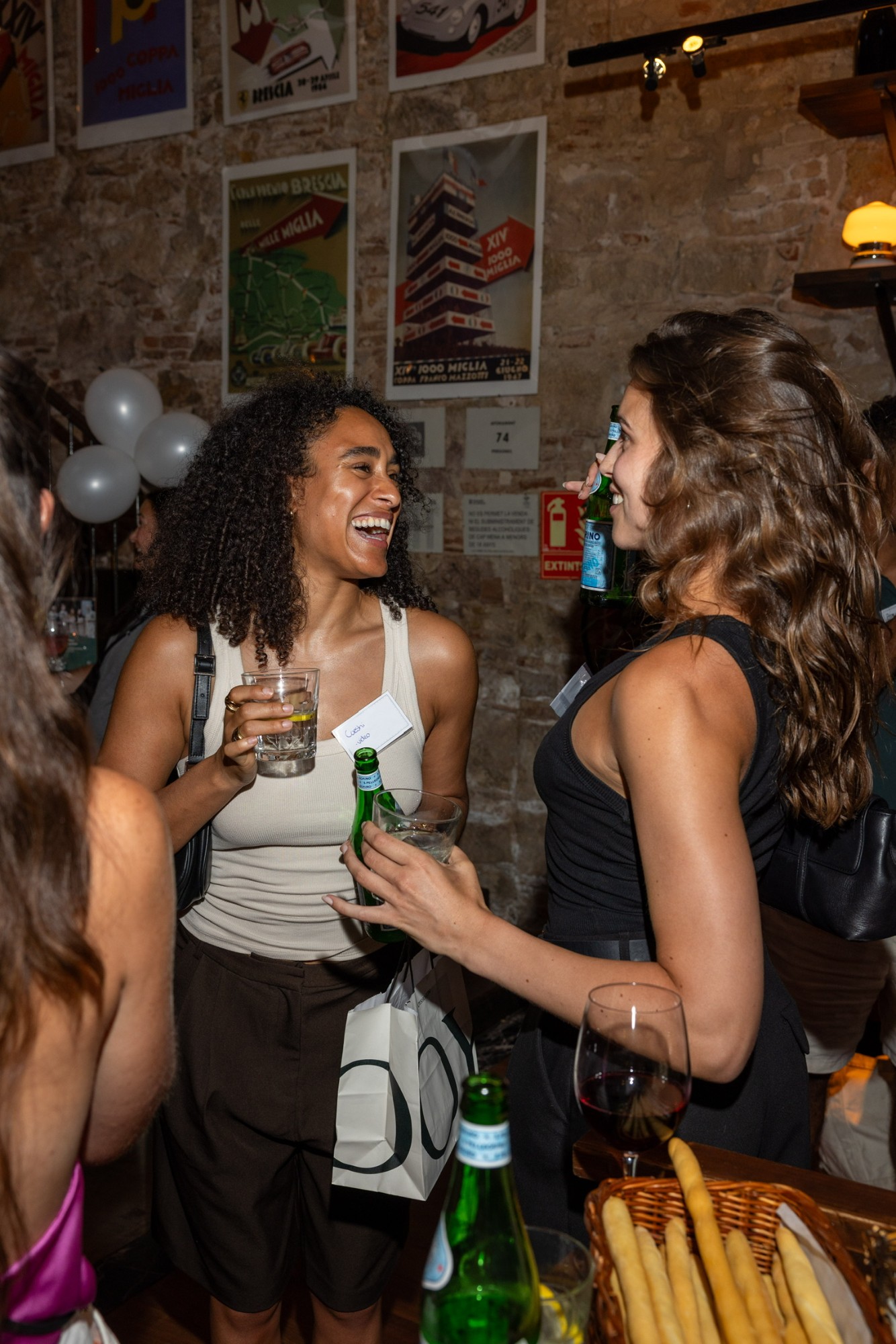 Guests talking over drinks against the restaurant's poster wall