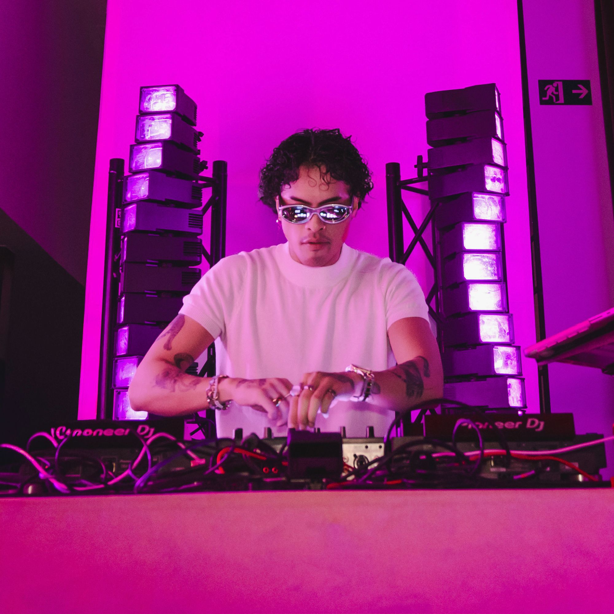 A DJ playing under pink light on the party night