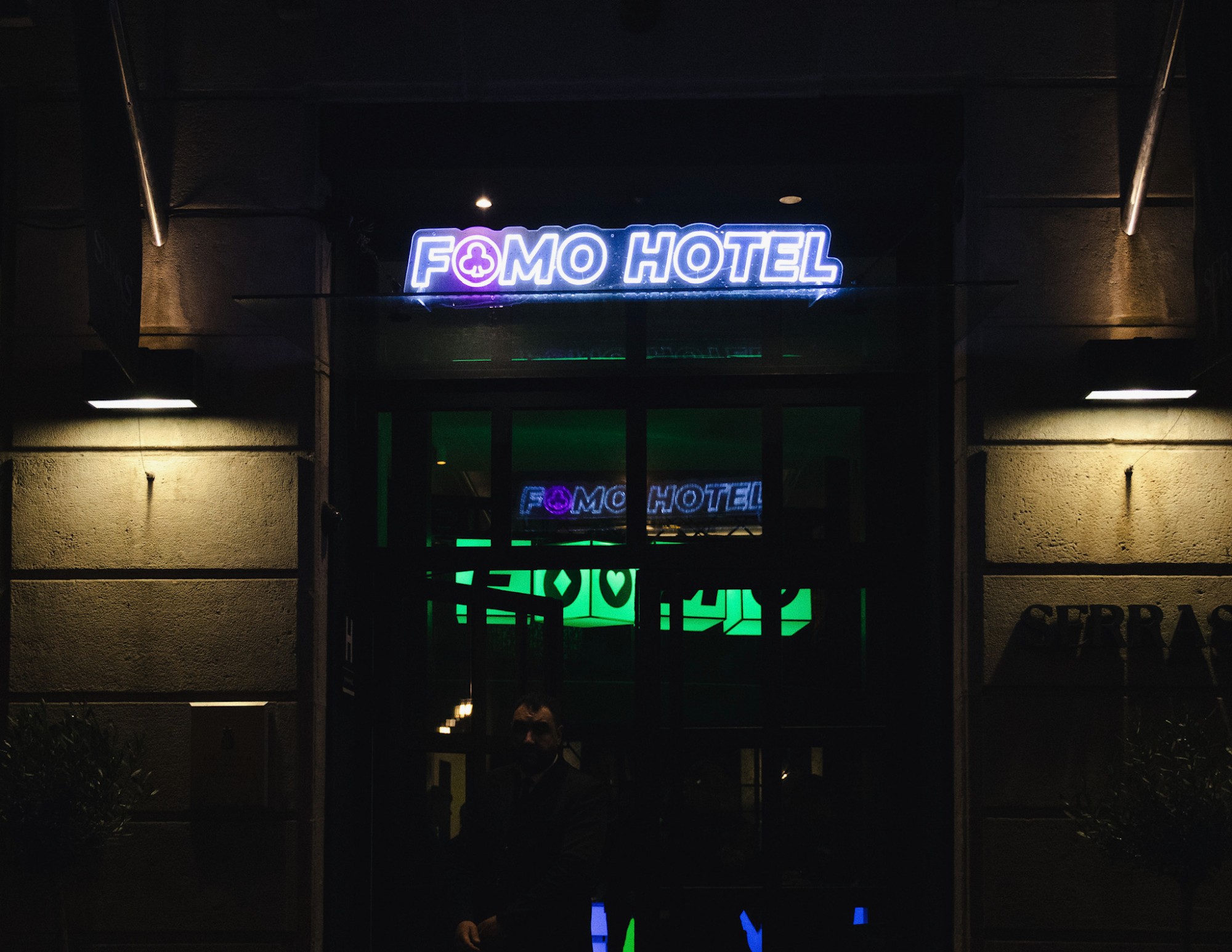 The hotel entrance at night under a neon FOMO Hotel sign