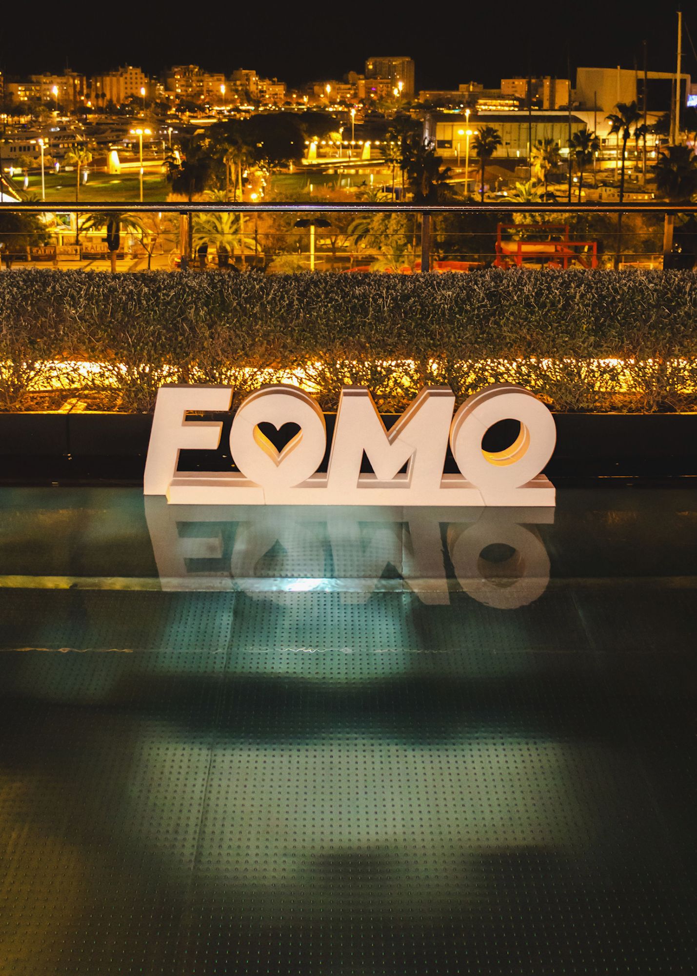 Illuminated brand letters beside the rooftop pool with the city lit up behind