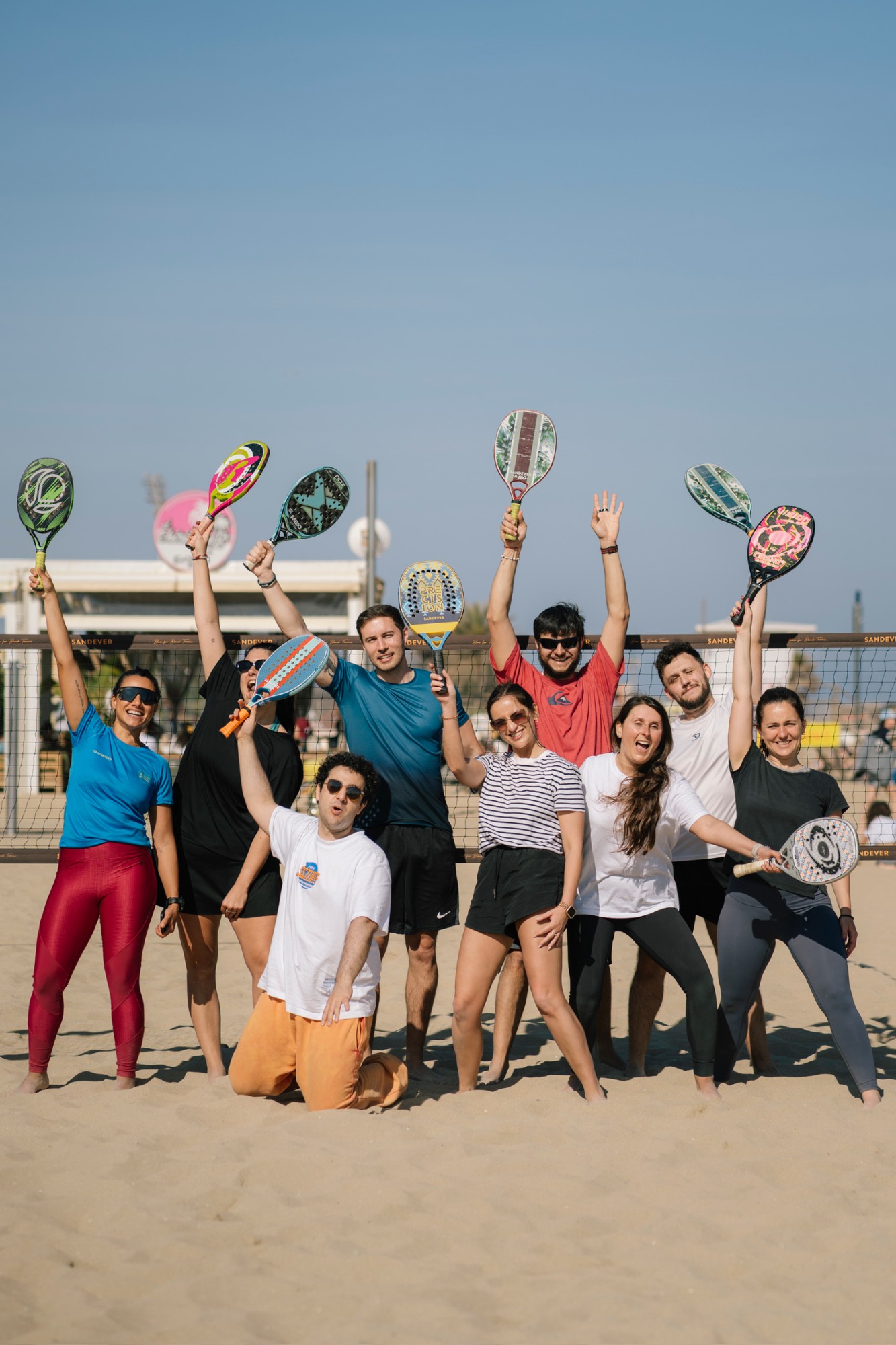 The group on the sand holding beach tennis rackets after a match