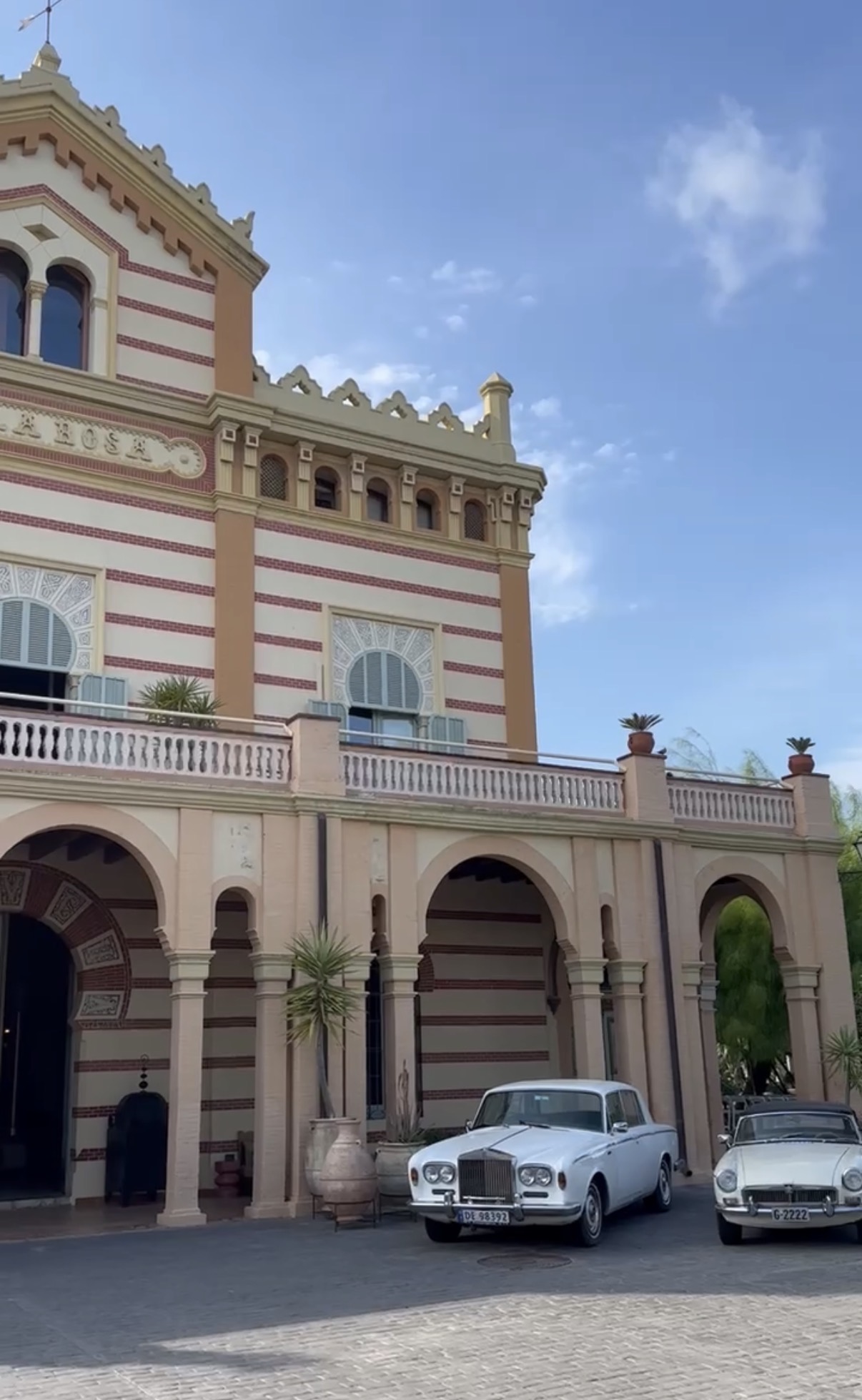 The villa facade with classic cars parked under the arches