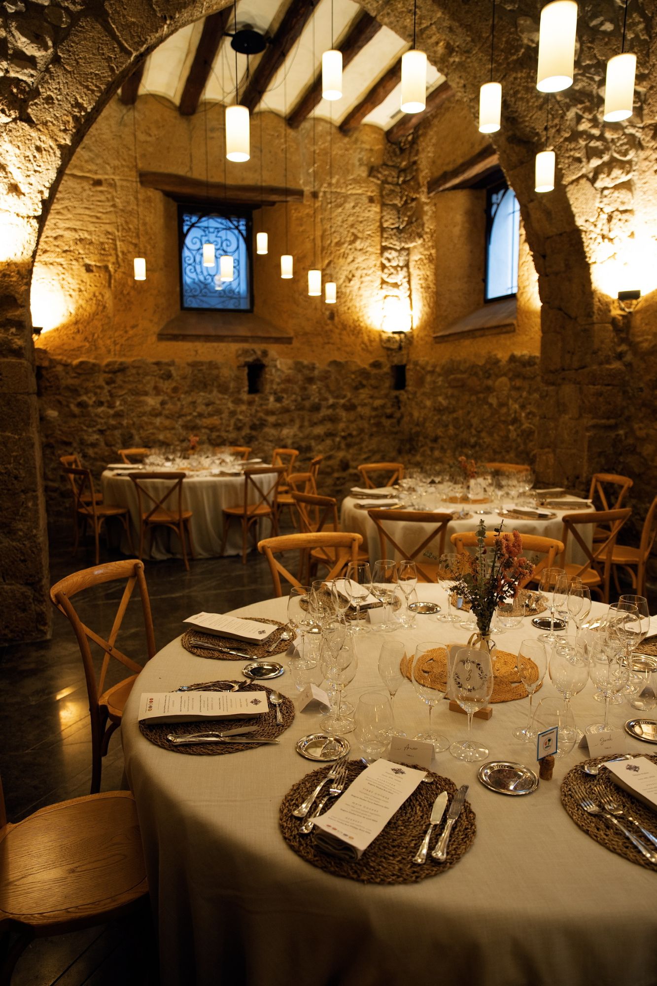 Round tables set for dinner in the winery's stone-vaulted room