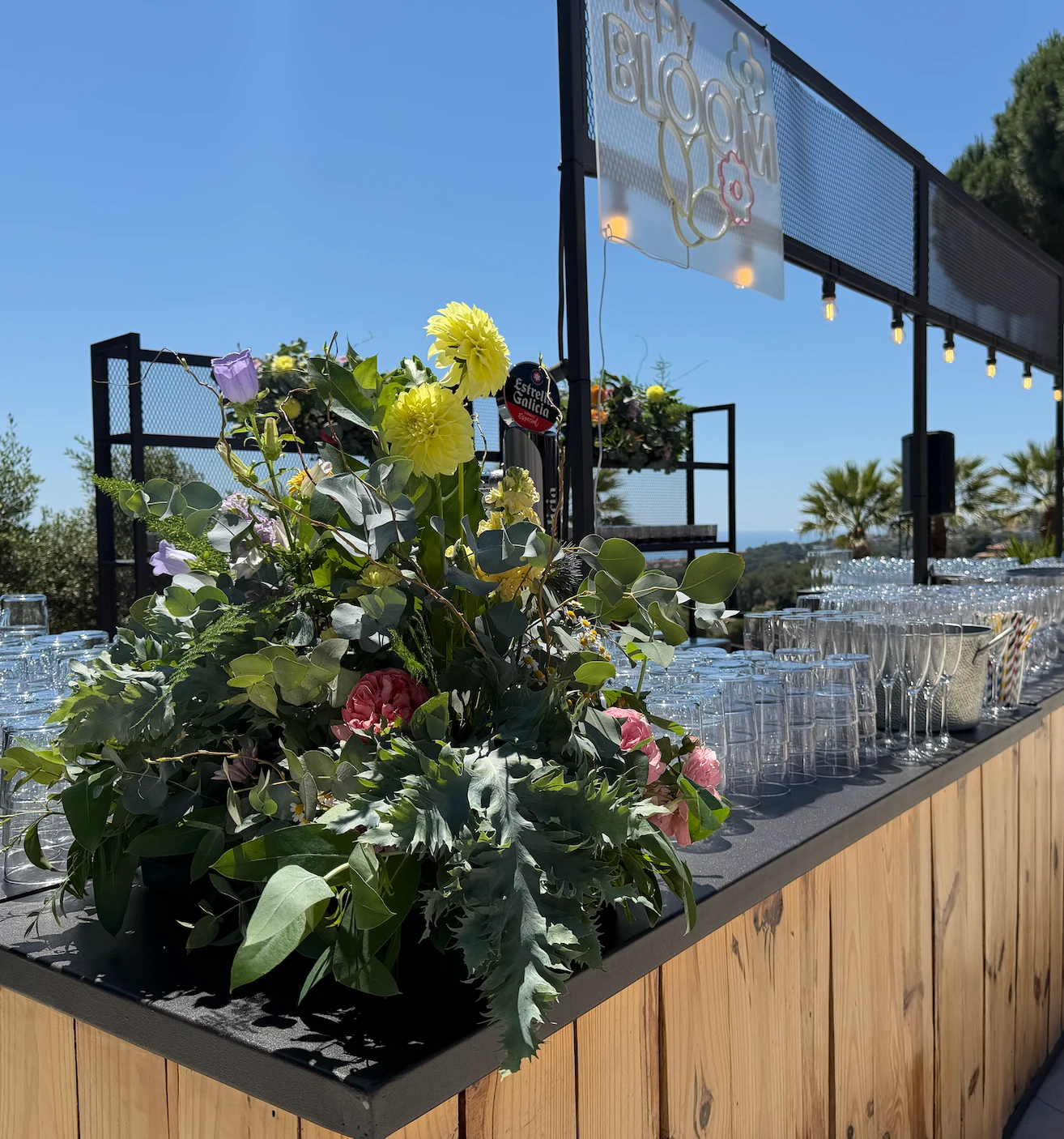 The garden bar dressed with florals under a Happy Bloom neon sign