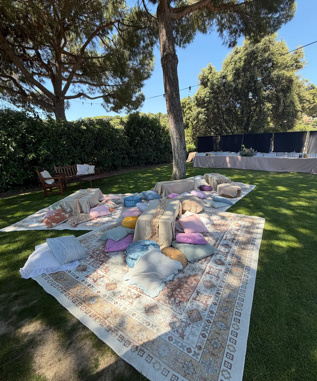 Rugs and cushions laid out under the pine trees as a chill-out area