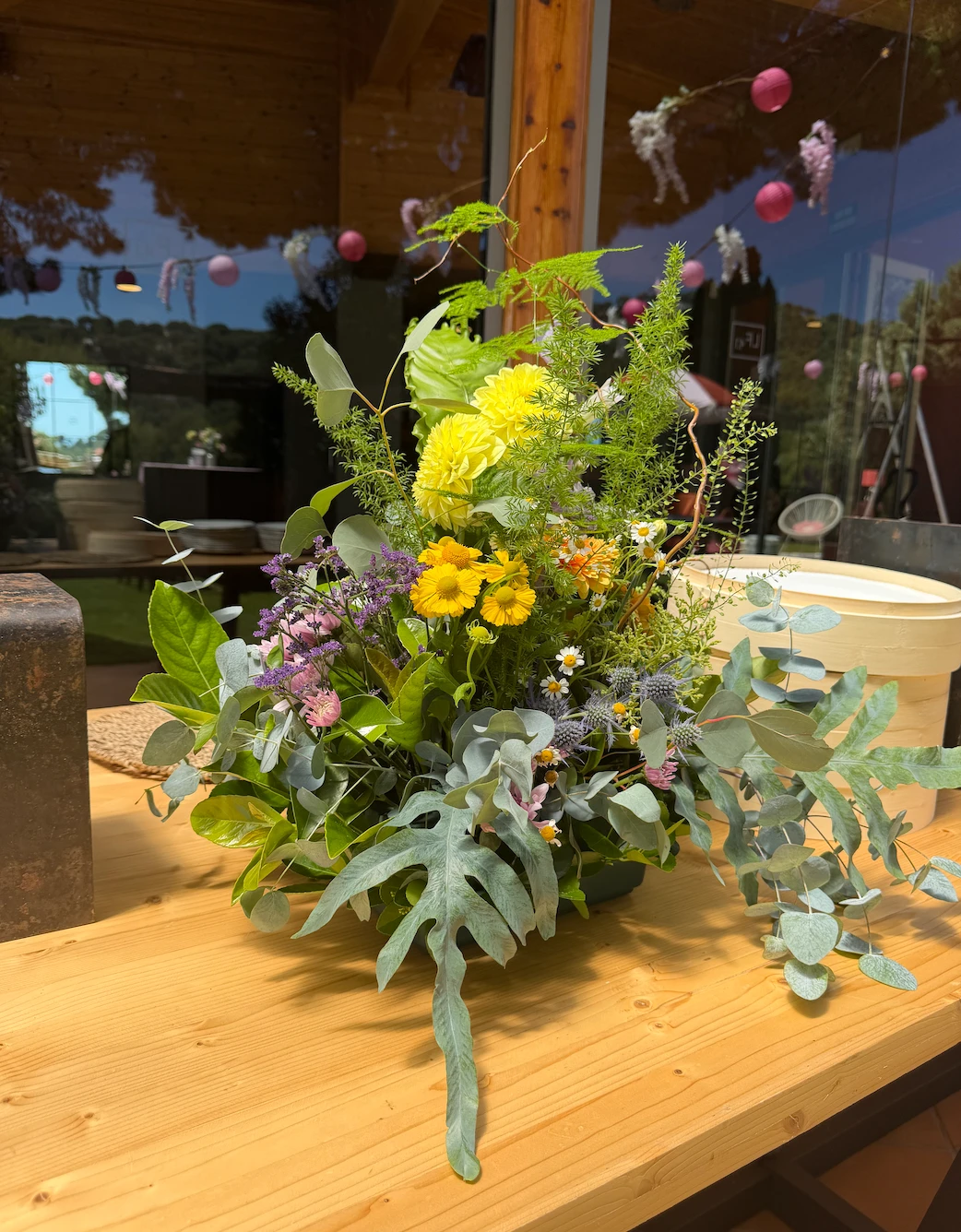 A seasonal floral arrangement on a wooden table beside the pavilion