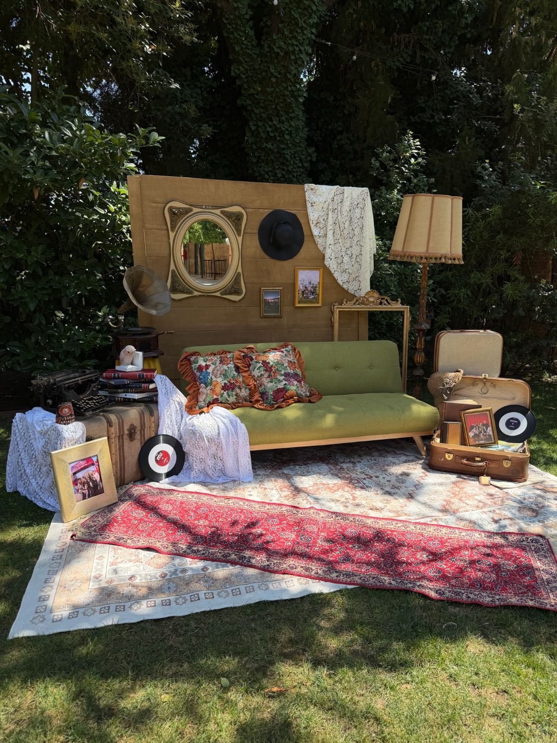 Vintage photo corner with a green velvet sofa, gramophone, typewriter and layered rugs
